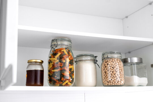 Organized kitchen pantry with dry food stored in glass jars