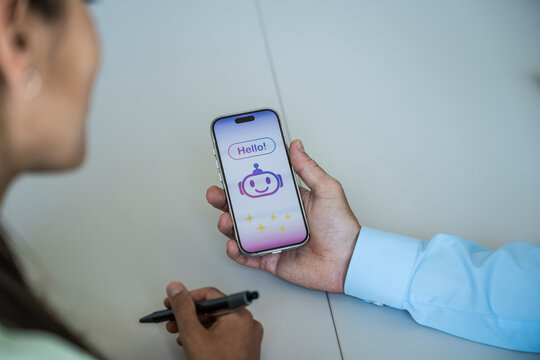 Man shows an AI chatbot on a smartphone to a woman at the office