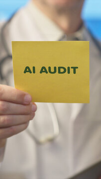 Medical professional holding a yellow sticky note displaying ai audit text, conceptualizing the critical need for artificial intelligence oversight and regulation in healthcare and technology