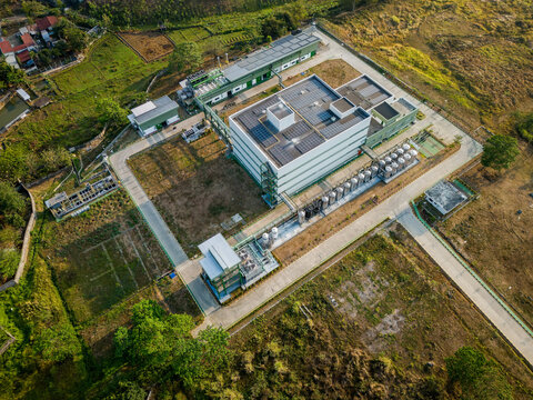 Aerial view of an industrial facility with solar panels on the roof, surrounded by rural landscape and vegetation in Semarang Regency, Central Java, Indonesia.