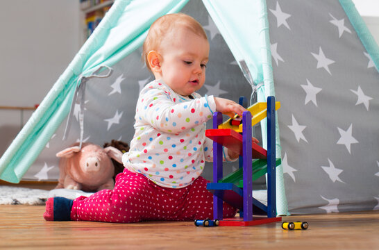 Baby girl playing with wooden toys on the floor at home