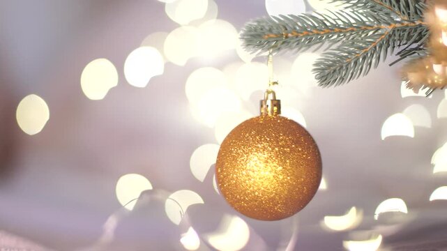 Golden Christmas Ball on Christmas Tree with light bokeh on background. New Year's festive Christmas balls decorate the Christmas tree. New Year's Eve