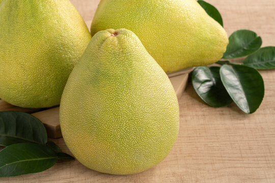 Fresh pomelo fruit with leaf on wooden table background.