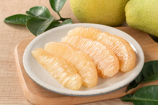 Fresh pomelo fruit with leaf on wooden table background.