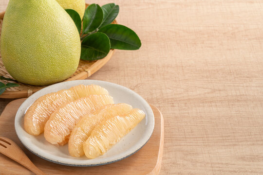 Fresh pomelo fruit with leaf on wooden table background.