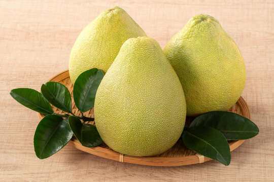 Fresh pomelo fruit with leaf on wooden table background.