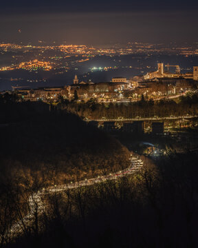 Aerial view of the illuminated town of Cingoli at night, featuring historic architecture and winding roads nestled in the hills of Cingoli, Marche, Italy.