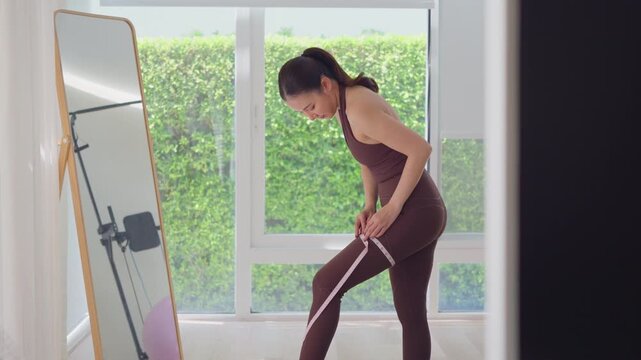 Rear view people young adult asian woman self tape measure hip leg size shape lean body mass index fat track weight loss perimenopause life anti aging diet preventive modern medicine asia health care.
