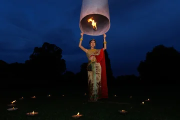 Thai Woman In Traditional Chut Thai Dress Releasing A Glowing Sky Lantern At Twilight During Loy Krathong Festival In Thailand © SHUTTER DIN