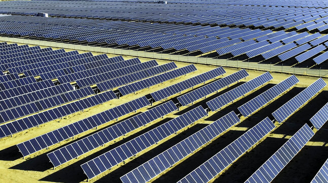 Aerial view of rows of solar panels lined up facing the sun in a vast renewable energy farm under clear skies in Los Angeles, California, United States.