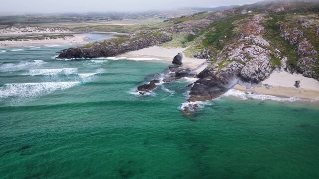 Aerial footage of rugged coastline with emerald ocean and sandy beaches on the Atlantic coast. Small sandy coves and secluded beaches of Barleycove Beach on the Mizen Peninsula in County Cork, Ireland
