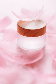  cosmetic product in a glass jar surrounded by soft pink feathers.Facial skin care. natural organic cosmetics. for product mockups, branding, natural cosmetics, and wellness 