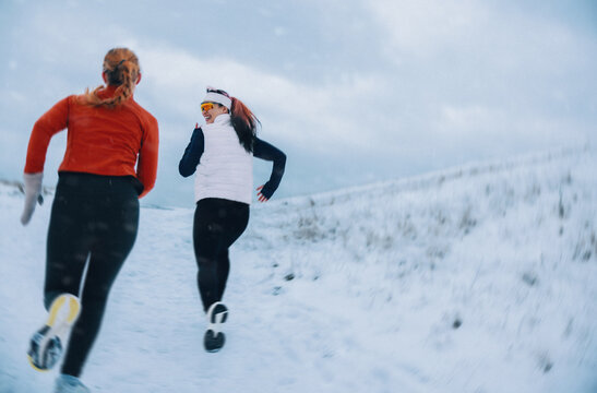 Together, women are running uphill on a snowy winter path