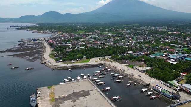 Tabaco Port in Albay, Philippines, with the perfectly shaped Mayon Volcano visible behind the vessel. Cinematic maritime transportation scene captured