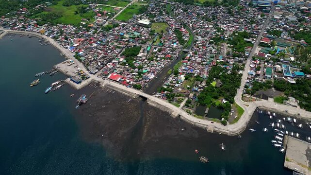 Aerial drone footage of Fatima Fish Port in Barangay Fatima, Tabaco City, Albay, Philippines. Coastal fishing facility with fishing boats and waterfront activity, showing the local fishing industry of