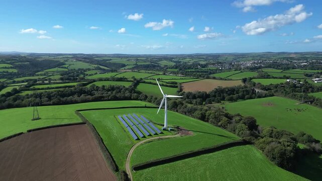 Liskeard, Cornwall, England: DRONE VIEWS: 1. Wind turbine with solar panel "farm"; 2. The town of Liskeard in the b/g. Wind power is an integral part of the UK government's strategy for net zero.