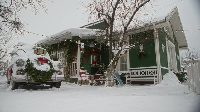 Decorated green cottage and retro car standing covered in winter snow with festive holiday wreaths. Footage suitable for Christmas seasonal marketing campaigns and winter holiday promo videos