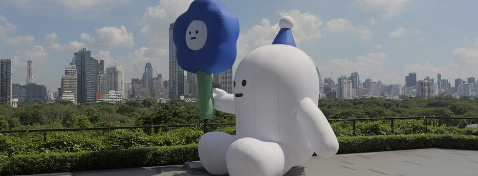 AH!Q a large white inflatable character holding a blue flower by Taiwanese artist Alan Hong sits on an open rooftop terrace at Central Park in Thai capital Bangkok