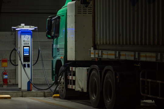 EV charging and semi truck electric vehicle, Electric vehicle semi truck trailer charging station for charge EV battery at night, EV charger semi truck trailer station at night.