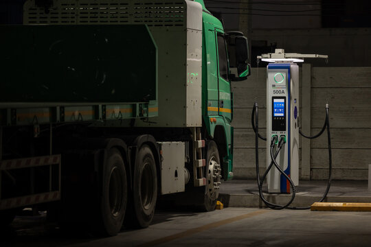 EV charging and semi truck electric vehicle, Electric vehicle semi truck trailer charging station for charge EV battery at night, EV charger semi truck trailer station at night.