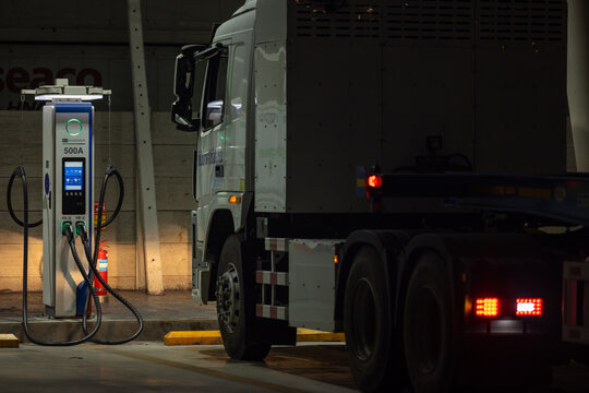 EV charging and semi truck electric vehicle, Electric vehicle semi truck trailer charging station for charge EV battery at night, EV charger semi truck trailer station at night.