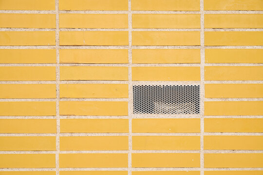 Close-up of a ventilation grille in a tlled wall.
