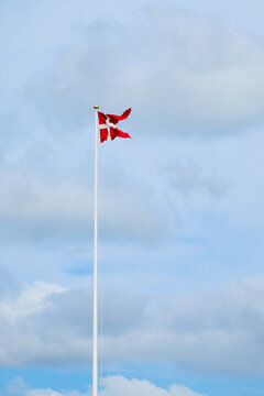 Danish flag on a mast waving in the wind.