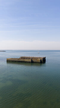 Aerial view of the historic concrete caissons at Inlaag Schelphoek, remnants of flood defenses, in the calm waters of the Oosterschelde in Serooskerke Schouwen, Zeeland, Netherlands.