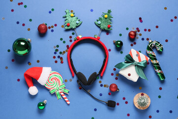 Obraz premium Holiday customer support and festive business communication, headset with christmas tree headband and seasonal decorations on a blue background