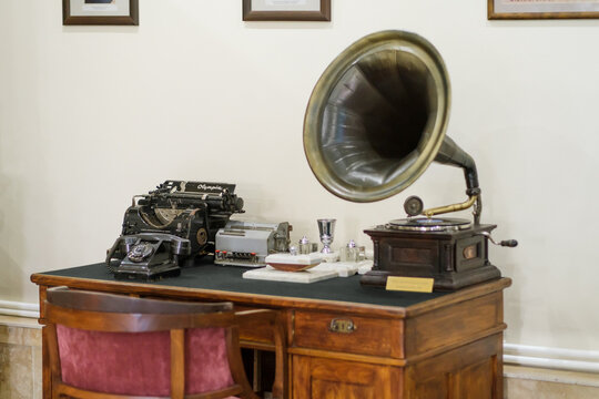 Yerevan, Armenia - August 27, 2026: Vintage gramophone and typewriter rest on a polished wooden desk beside small objects and framed pictures in a noah brandy factory