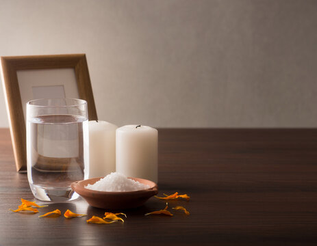Water, salt and candles on a Day of the Dead ofrenda with unread photograph