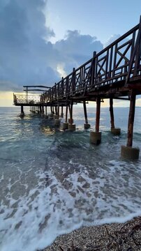 Peaceful Mediterranean Morning with a Weathered Wooden Pier and Blue Sea
