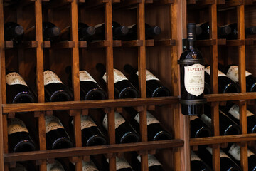 Naklejka premium Patardzeuli, Georgia - September 03, 2026: Wooden rack holds rows of dark wine bottles, with a labeled saperavi bottle displayed prominently among cellar storage