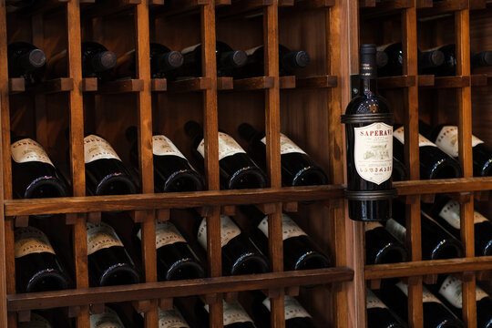 Patardzeuli, Georgia - September 03, 2026: Wooden rack holds rows of dark wine bottles, with a labeled saperavi bottle displayed prominently among cellar storage