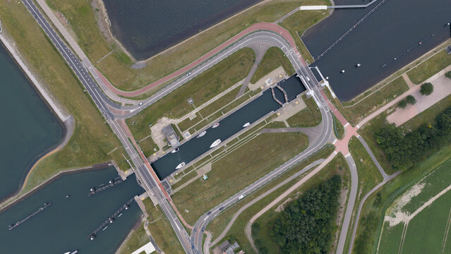 Aerial view of Zandkreeksluis lock complex with boats in the water, surrounded by green fields, roads, and waterways in Kortgene, Zeeland, Netherlands.
