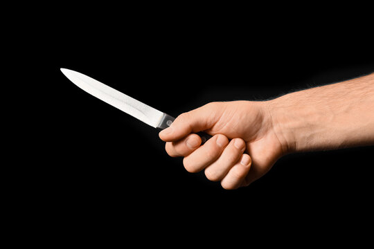 Crime and violence threat, hand holding a sharp kitchen knife on black background