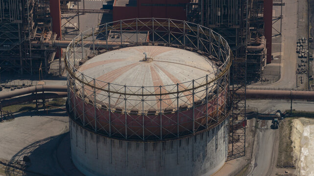 Aerial view of the ArcelorMittal industrial facility featuring a large circular gas holder with metal framework, pipes, and infrastructure in Dunkerque, Hauts-de-France, France.