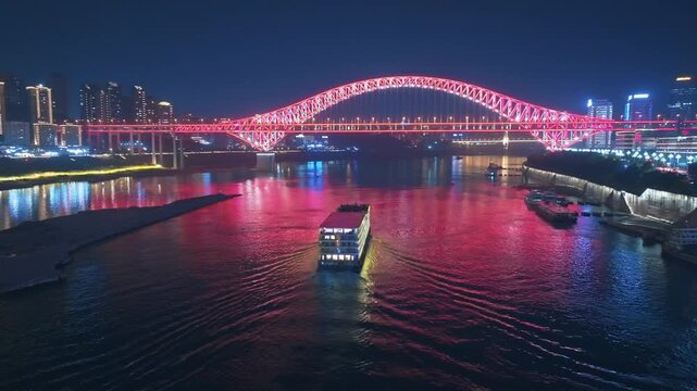 Illuminated Red Arch Bridge Over River With Cruise Ship In Chongqing At Night in Chongqing, China