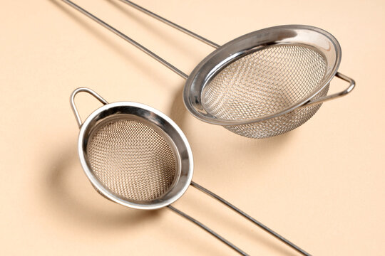 Food preparation and culinary tools, two stainless steel kitchen strainers for cooking and baking on a neutral background
