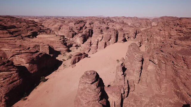 an aerial view displays a vast, rugged desert terrain featuring a network of deep sandy corridors and weathered red rock formations stretching into the distance.