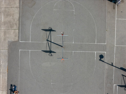 Aerial view of the basketball court at Poinsettia Recreation Center with clear court markings and long shadows cast on the asphalt surface in Los Angeles, California, United States.
