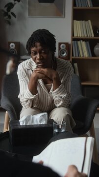 Vertical video of distressed African American young woman talking during psychotherapy session with psychologist. Footage suitable for mental health campaigns and therapy promotion