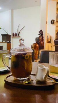 Vertical close-up of hot herbal tea with red dates and longan served on a wooden tray in a cozy cafe