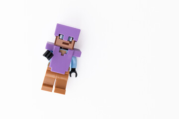 Naklejka premium Lego Minecraft Steve mini-figure in purple clothes and helmet, shot isolated on a white background with room for copy space. Bradford, UK Oct 2 2026