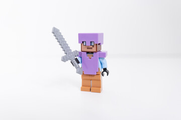 Naklejka premium A purple Lego Minecraft Steve mini-figure holding a silver sword shot isolated on a white background. Bradford, UK Oct 2 2026