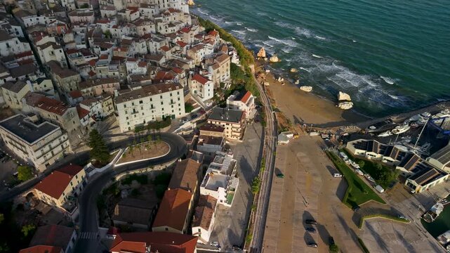 Rodi Garganico Puglia Italy 4k drone view of marina boats in morning light. Dynamic ascending turn reveal of authentic whitewashed town, adriatic sea waves b-roll  scenic establishing shot waves sound