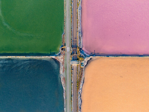 Aerial view of the colorful salt ponds at Bedwell Bayfront Park featuring vibrant green, pink, and orange water basins separated by narrow dirt paths in Menlo Park, California, United States.