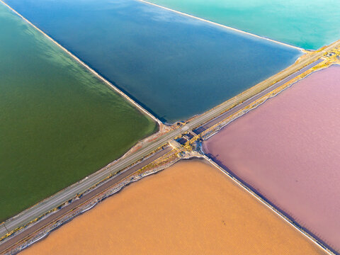 Aerial view of the colorful salt evaporation ponds at Bedwell Bayfront Park with geometric levees and roads in Menlo Park, California, United States.