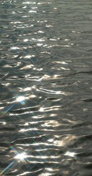 Star Filter Turns Sunlit Water Reflections into Sparkles. Sunlight reflections dance across water through star filter. Ripples carry bright, star shaped glints that create luminous, tranquil pattern.