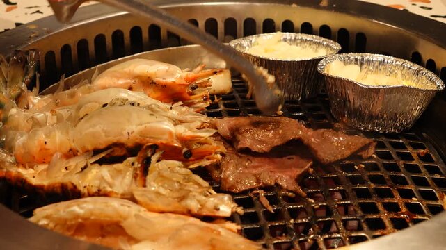 Close up of Wagyu Hoba Yaki beef grilled on dried leaf. Grill shrimps barbecue on hot coal in the restaurant. VDO 4k close up the cooked grill shrimps. Time lapse people are eating sea food. 